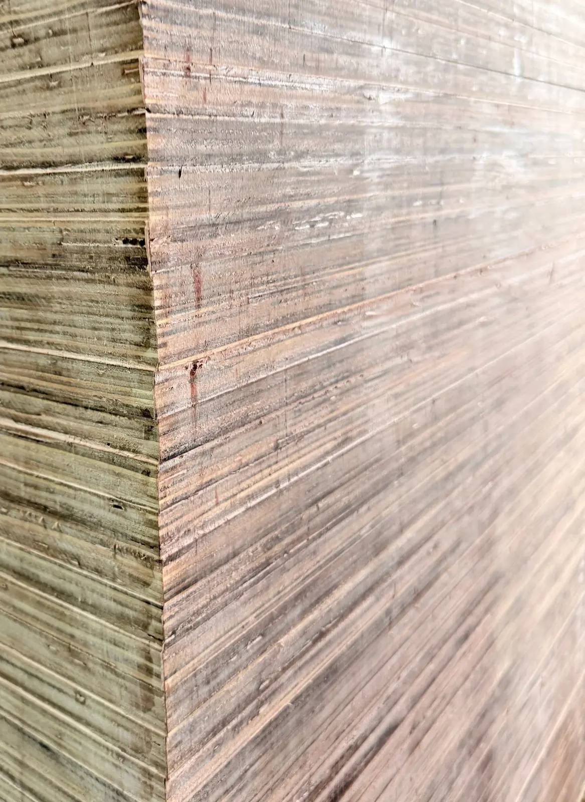 Close view of the corner of a tall pack of film-faced plywood, many layered sheet edges